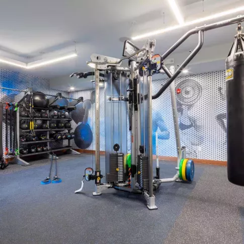 Functional training area equipped with a multi-station weight machine, punching bag, resistance bands, and medicine balls, designed for high-intensity workouts at The Everly Luxury Apartments.
