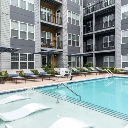A luxurious resort-style pool surrounded by lounge chairs and umbrellas, providing a relaxing retreat for residents at The Everly Luxury Apartments.
