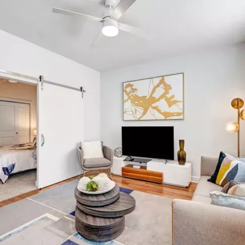 A contemporary living room featuring a stylish TV console, plush seating, and a decorative gold-accented artwork for an elegant touch.