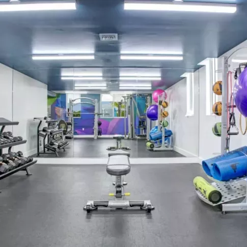 Fully equipped fitness center at 275 Fontaine Parc featuring free weights, exercise balls, and vibrant wall art for an energizing workout environment.
