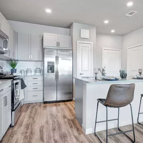Contemporary kitchen with a sleek design, featuring granite countertops, stainless steel appliances, and a cozy breakfast bar with leather stools.