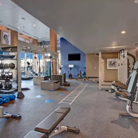 Expansive gym with state-of-the-art machines and a vibrant mural at The Pacific Luxury Apartments.