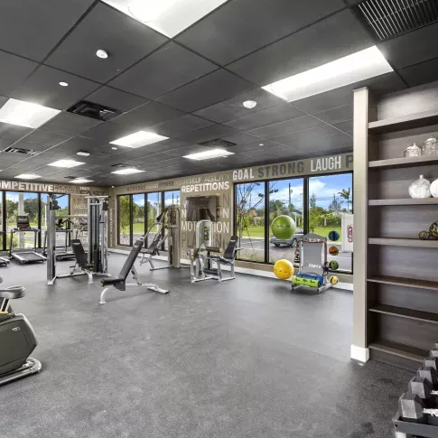 A spacious gym with state-of-the-art exercise equipment and motivational wall graphics, designed for an active lifestyle at Pine Ridge Luxury Apartments.