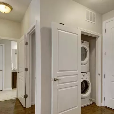 A utility space with a stacked washer and dryer conveniently located near the entryway of the apartment.