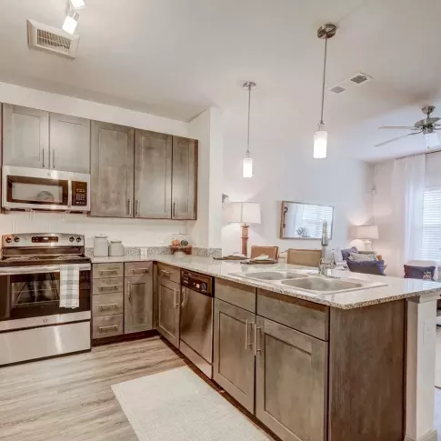 Upscale kitchen with stainless steel appliances, granite countertops, and pendant lighting at The Emerson at Forney Luxury Apartments.