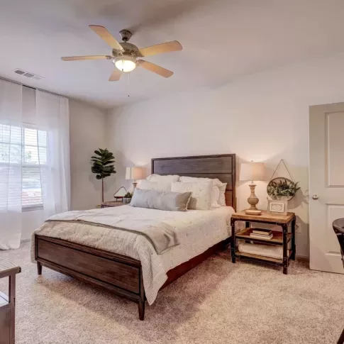 Spacious master bedroom with elegant decor, plush carpeting, and large windows at The Emerson at Forney Luxury Apartments.