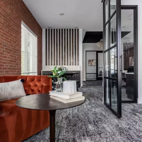 Intimate seating area featuring a vibrant orange sofa, modern decor, and a cozy atmosphere perfect for relaxation or meetings.