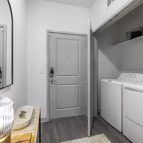 A convenient in-unit laundry space with a stacked washer and dryer, built-in shelving, and sleek modern finishes.