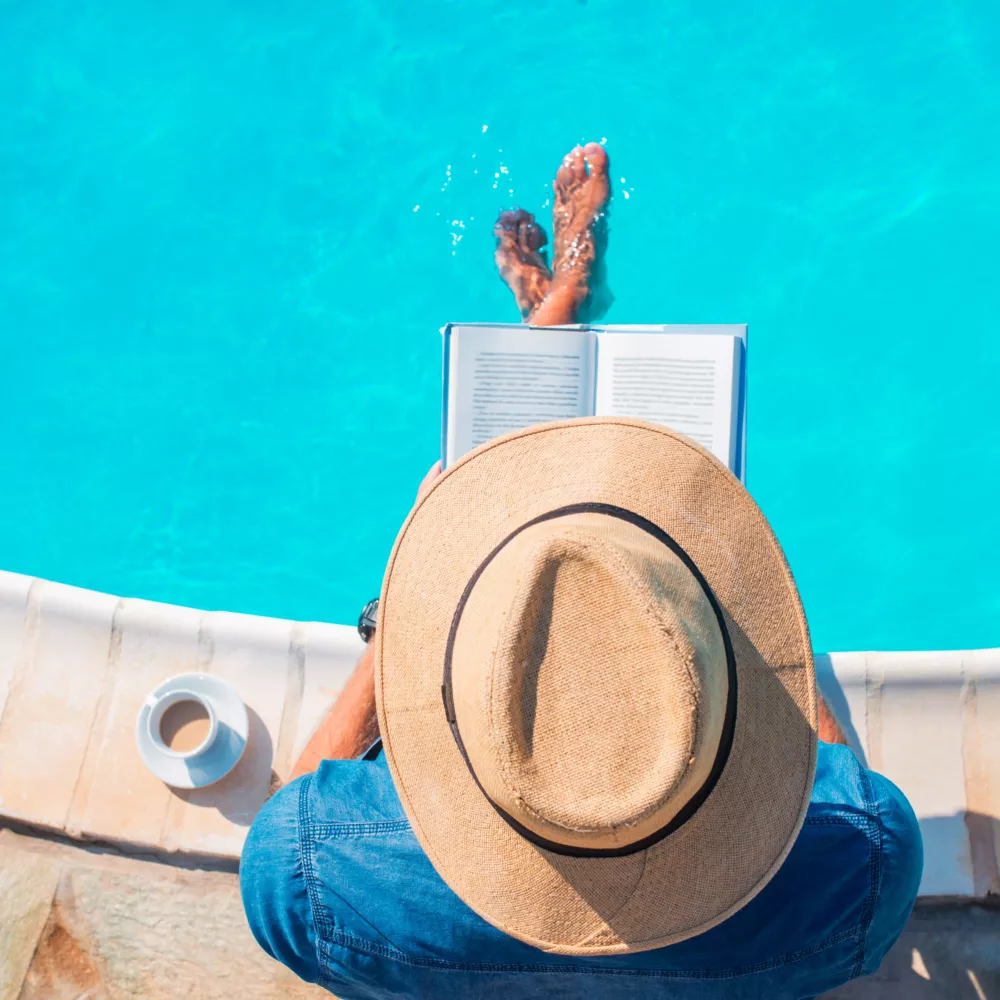 Person sits and reads by the pool