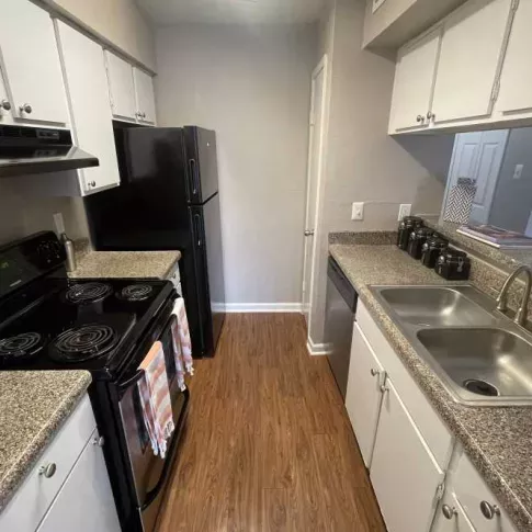 A spacious kitchen at The Oaks of Westchase Apartments featuring black appliances, sleek countertops, and ample cabinet storage.
