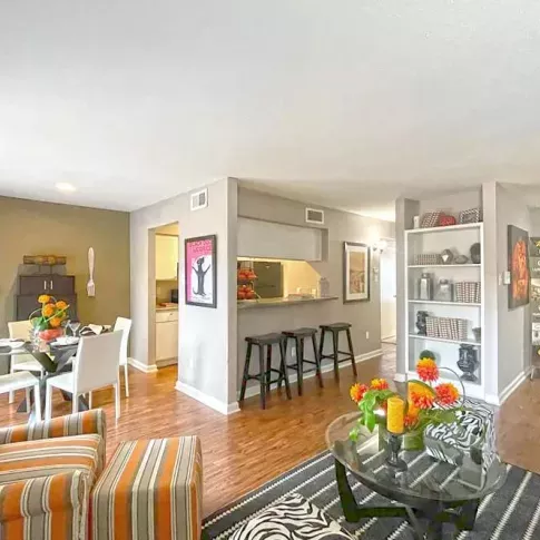 An open-concept living and dining area with hardwood-style flooring, built-in shelving, and chic furnishings.