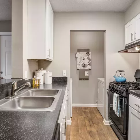 Kitchen at The Samuel with black countertops, white cabinetry, black appliances, and adjacent laundry space