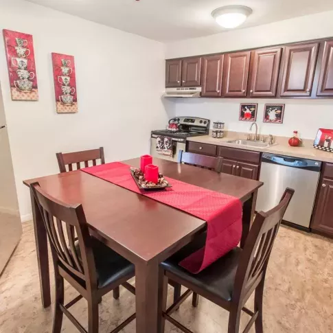 Modern kitchen and dining area at Silver Lake Manor Apartments, featuring dark wood cabinetry, stainless steel appliances, and stylish red decor accents for a warm and inviting atmosphere.