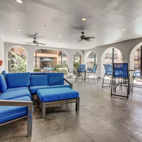 Covered outdoor lounge at The Saulet luxury apartments in New Orleans with modern blue cushioned seating and poolside views.
