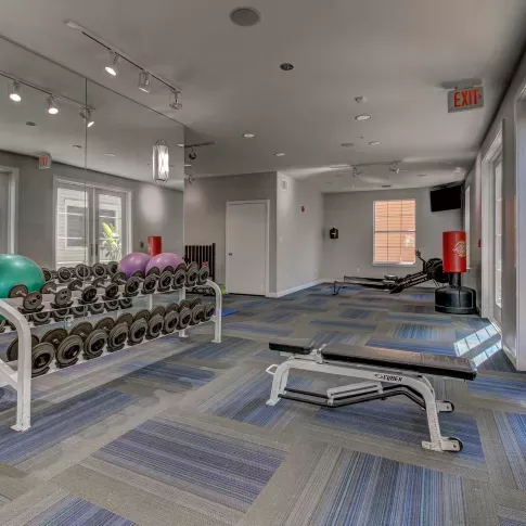 The Saulet apartment gym with dumbbell rack, flat bench, and strength training equipment in New Orleans, LA.