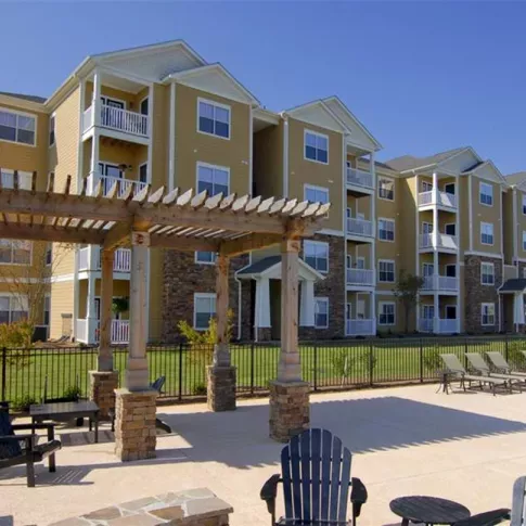 Modern four-story apartment buildings at Knob Creek Apartments with balconies, stone accents, and a pergola-covered seating area.