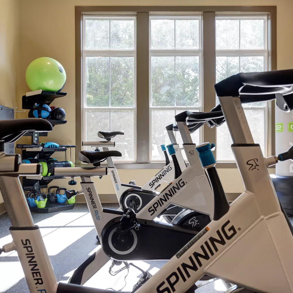Group cycling studio with stationary bikes and natural light at Tapestry Turkey Creek apartments.