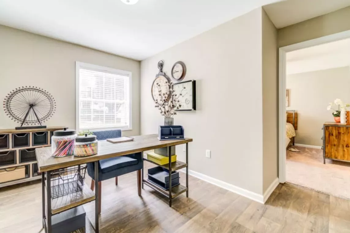 Bright home office space featuring a large desk, modern decor, and ample natural light from a nearby window, creating a productive and stylish work environment.