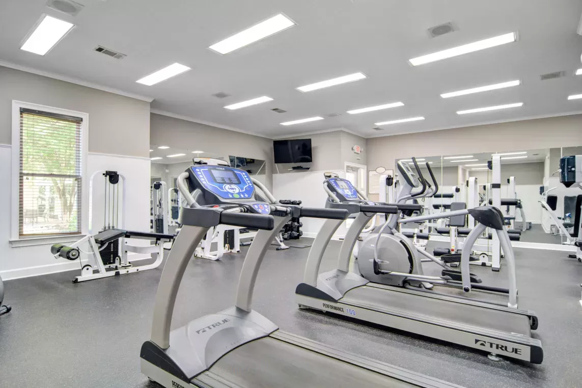 A well-equipped fitness center featuring treadmills, strength training machines, and ample space for a complete workout in a bright, modern setting.