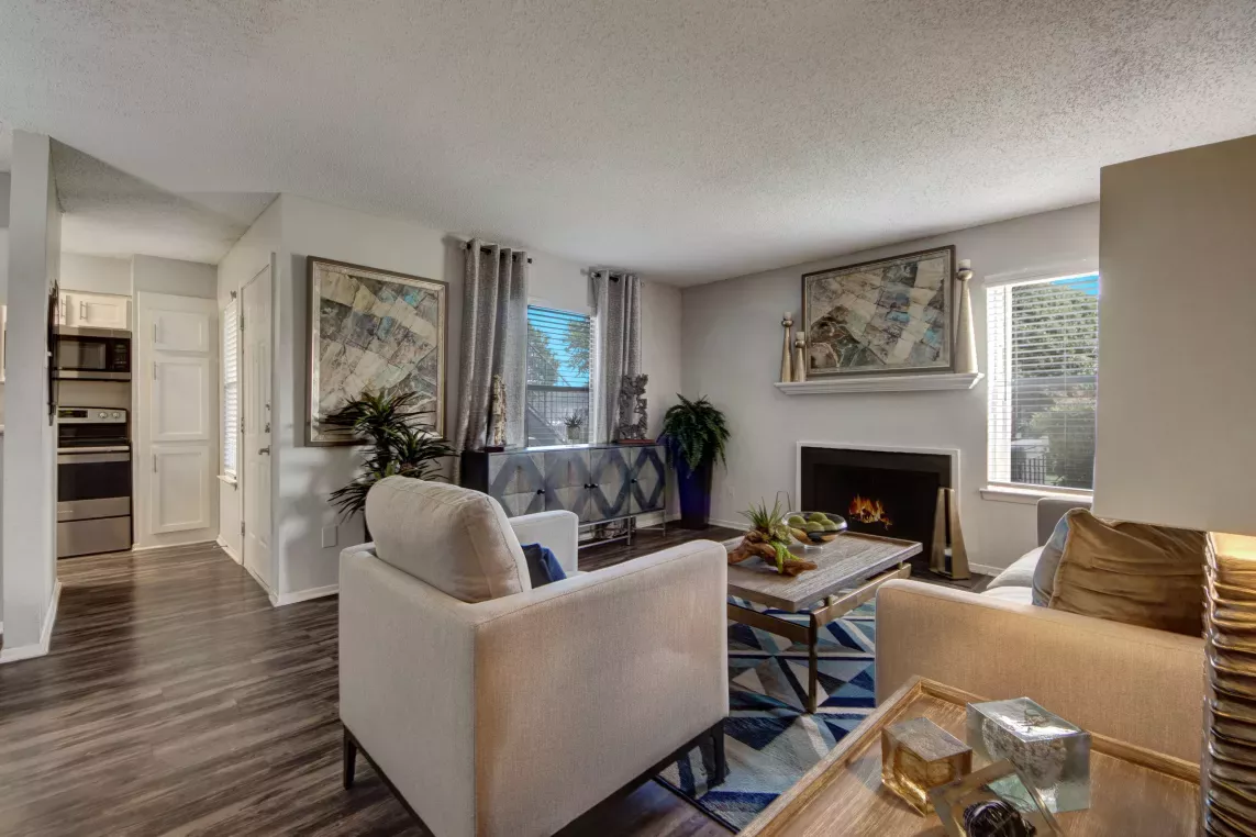 A cozy living room featuring a fireplace, modern furniture, and decorative artwork with natural light streaming through the windows.