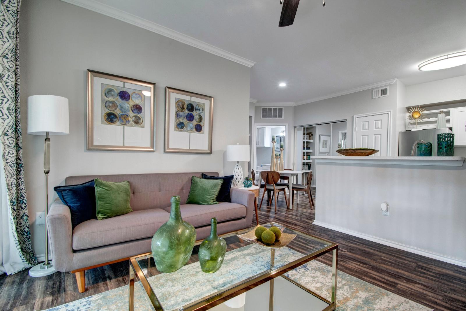 A cozy living room with modern decor, featuring a sofa, glass coffee table, and framed art on the wall.