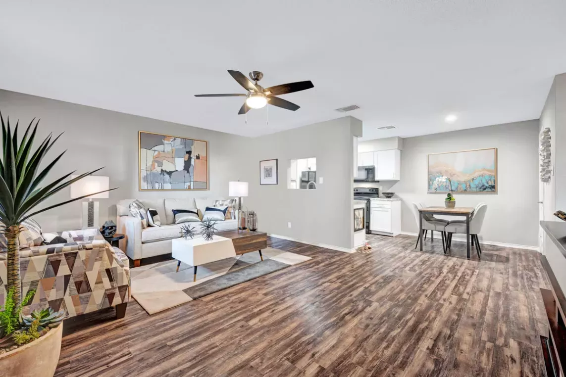 Open-concept living space with stylish wood flooring, a cozy living room setup, dining area, and modern kitchen, complemented by neutral tones and natural lighting for a warm and inviting atmosphere.