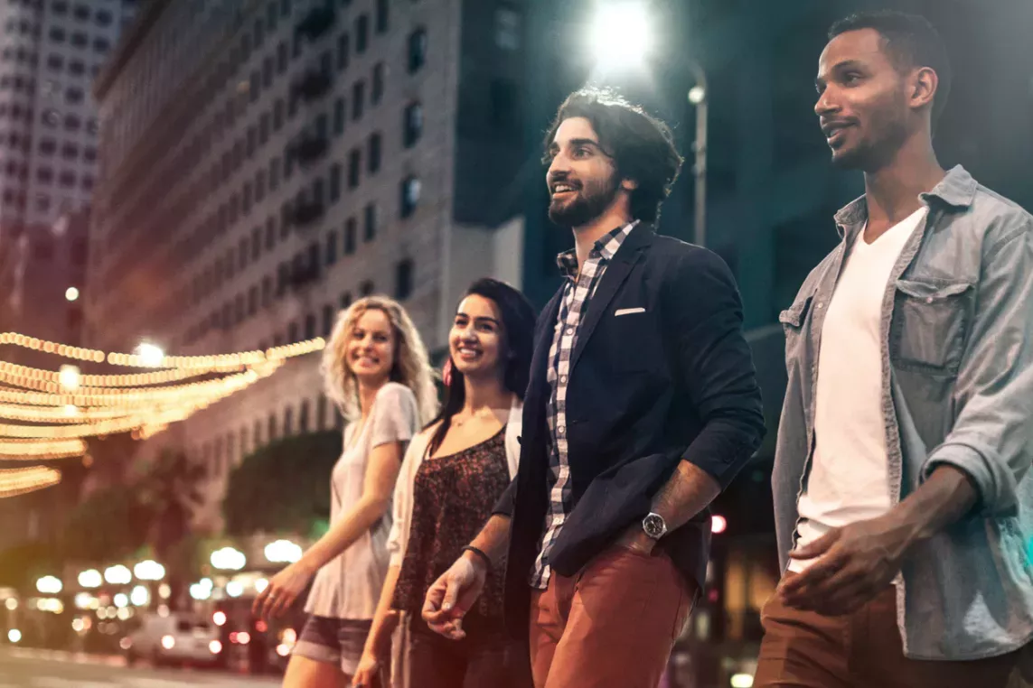Group of friends enjoying a vibrant night out in a bustling city, surrounded by lively lights and urban energy.
