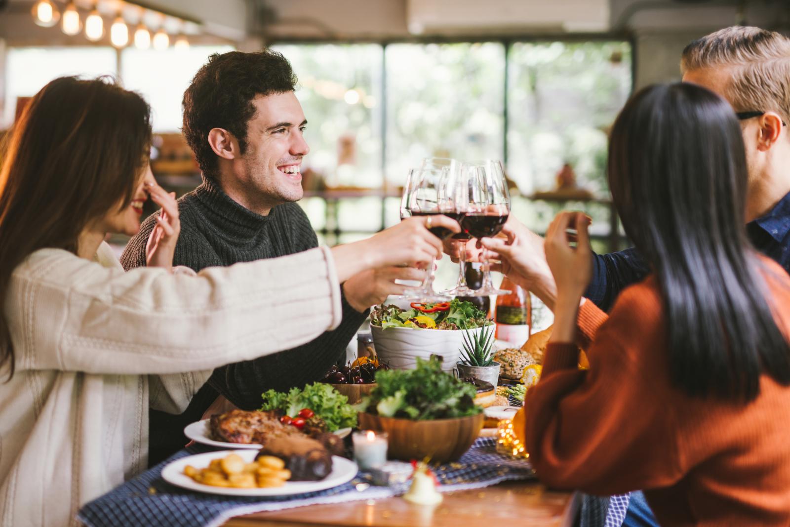 Cheers to good times and great company! A group of friends clinking glasses filled with wine at a joyful gathering. Laughter and warmth fill the atmosphere, with delicious food and a cozy setting creating the perfect ambiance for a memorable evening.