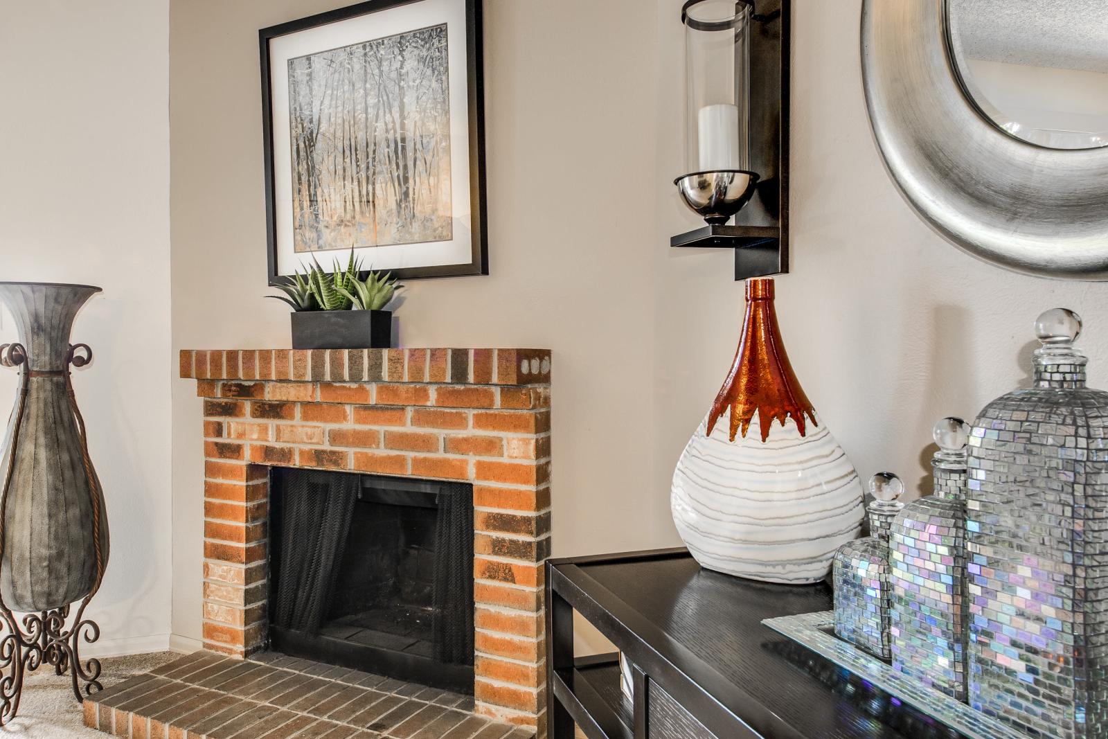 A cozy corner with a brick fireplace, decorative artwork, and modern accent pieces.