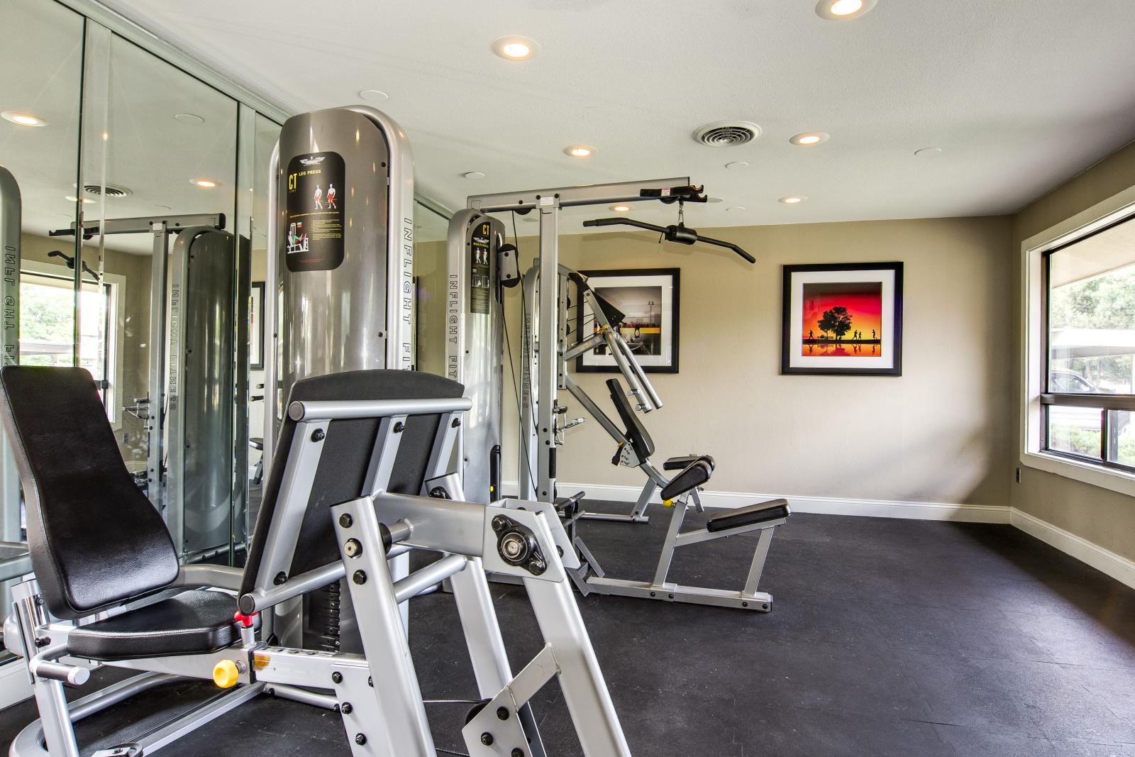 A well-lit fitness center with modern exercise equipment and mirrored walls.