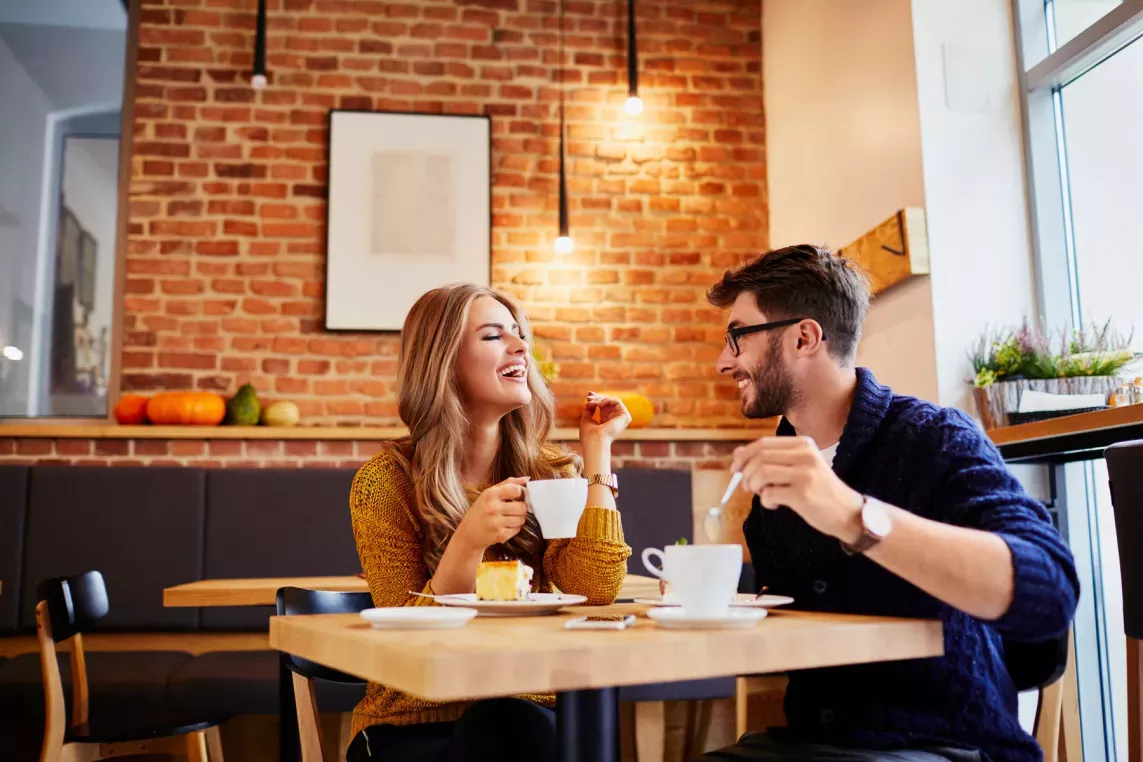 Couple having drinks at a warm cafe with a brick wall and natural light.