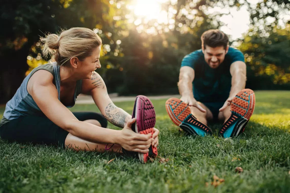 Woman and man stretching on lawn