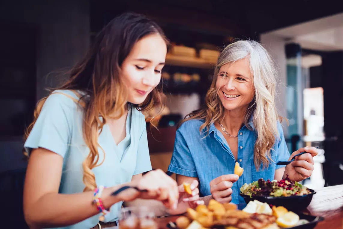 Two women enjoying a meal together at a cozy restaurant, smiling and engaging in conversation. This image highlights the vibrant dining and social opportunities near Broadview Oaks Apartments.