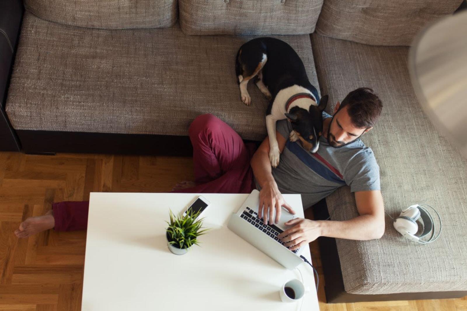 Man working on laptop while sitting with dog