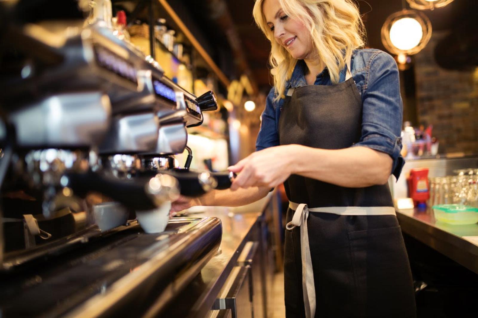 Barista pouring a cup of coffee from a coffee machine