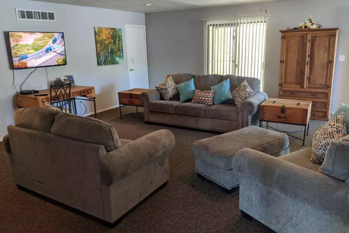 A cozy clubhouse with comfortable sofas, a dining area, and a mounted TV, creating an inviting space for residents to gather and relax