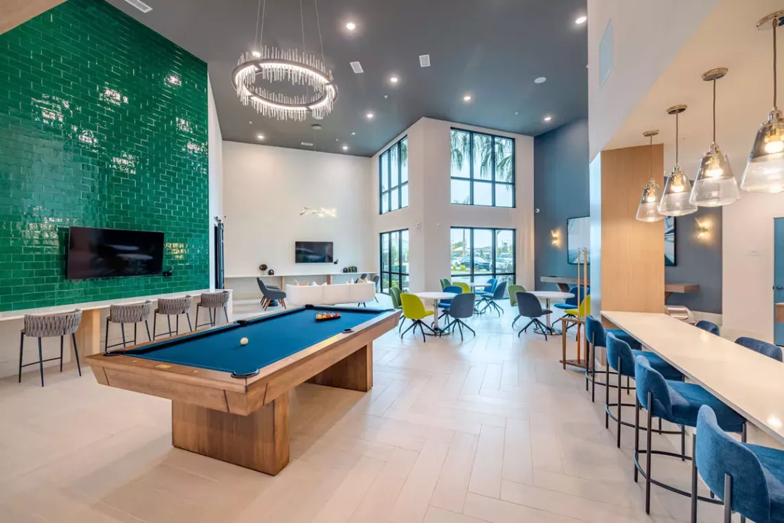 Image 6: Luxurious game room with a billiards table, cozy seating areas, and contemporary lighting at Tropia Wellen Park Apartments.
