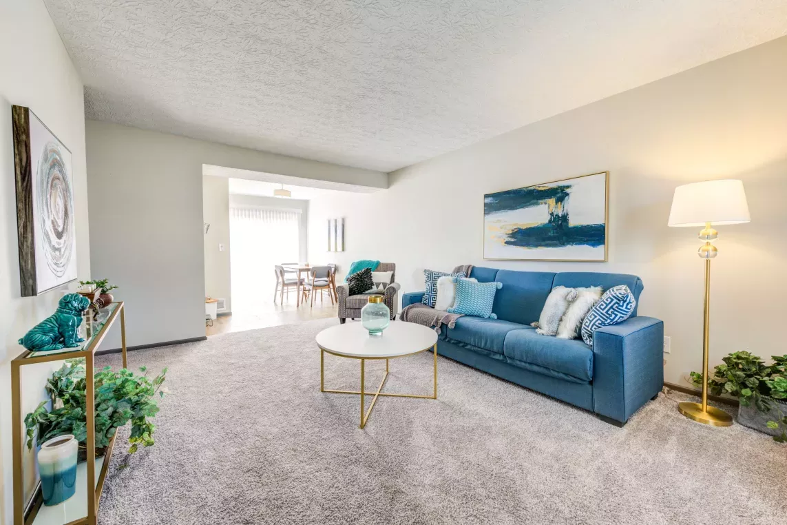 Comfortable living room with a navy sectional couch, decorative pillows, and stylish decor at Worthington Meadows Apartments.