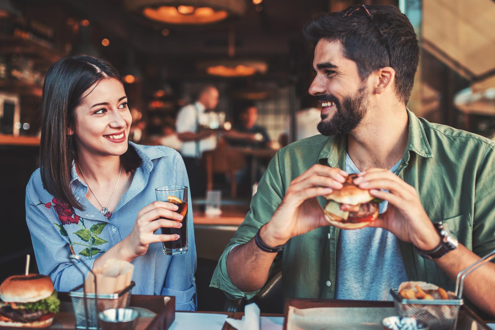 A man and a woman enjoy a casual meal together, smiling and sharing conversation at a restaurant.