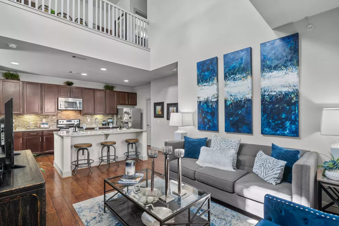 A spacious living area with a kitchen in the background, showcasing an open-concept design at Arrabella Apartments.