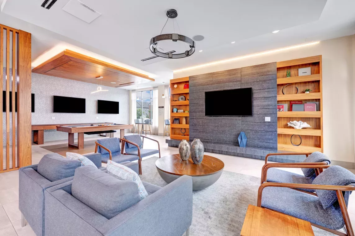 A sophisticated resident lounge featuring plush seating, a billiards table, mounted flat-screen TVs, and sleek modern décor, designed for comfort and socializing.
