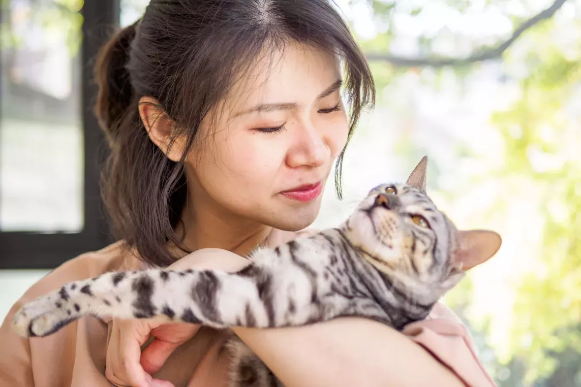 Woman holding a striped cat