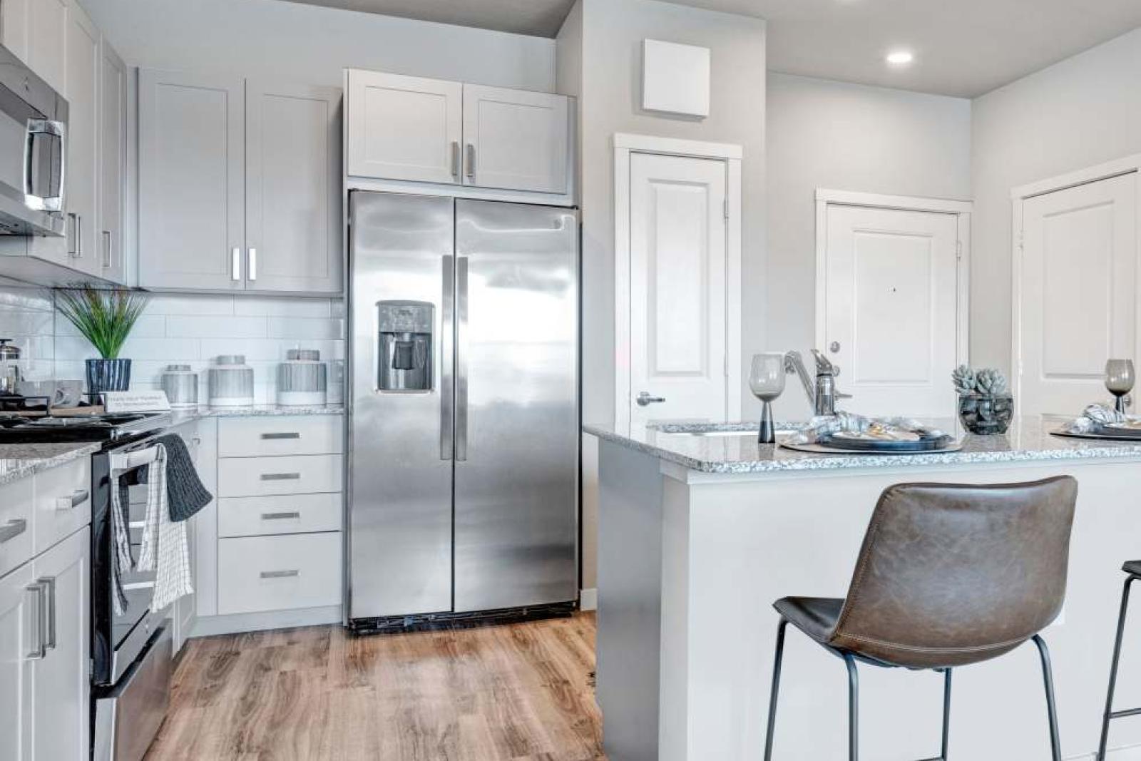 Contemporary kitchen with a sleek design, featuring granite countertops, stainless steel appliances, and a cozy breakfast bar with leather stools.