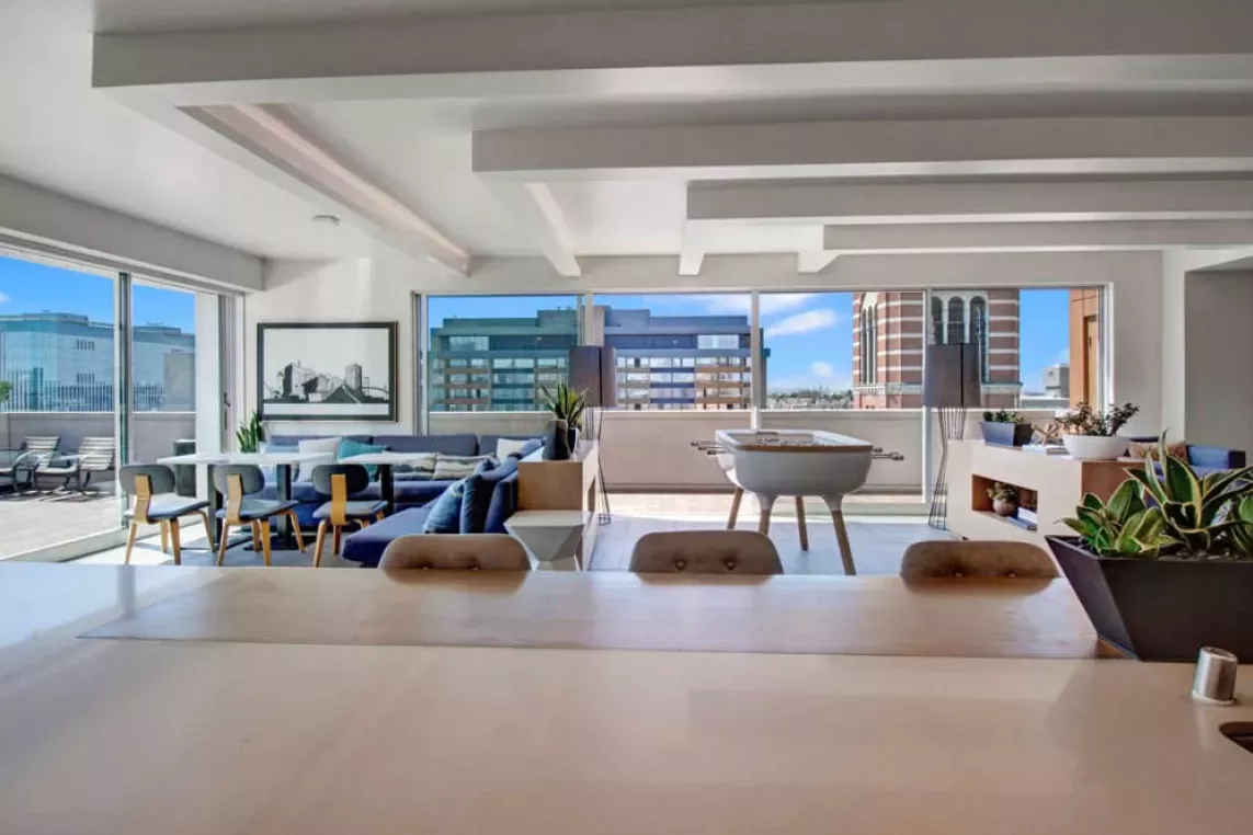 Rooftop lounge with open seating, a foosball table, and panoramic city views at The Pacific Luxury Apartments.