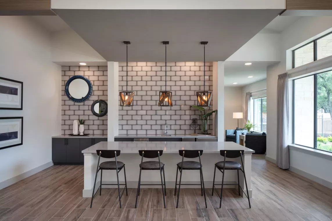 A stylish resident lounge with a sleek bar area, pendant lighting, and contemporary decor offers a sophisticated space for socializing and relaxation.