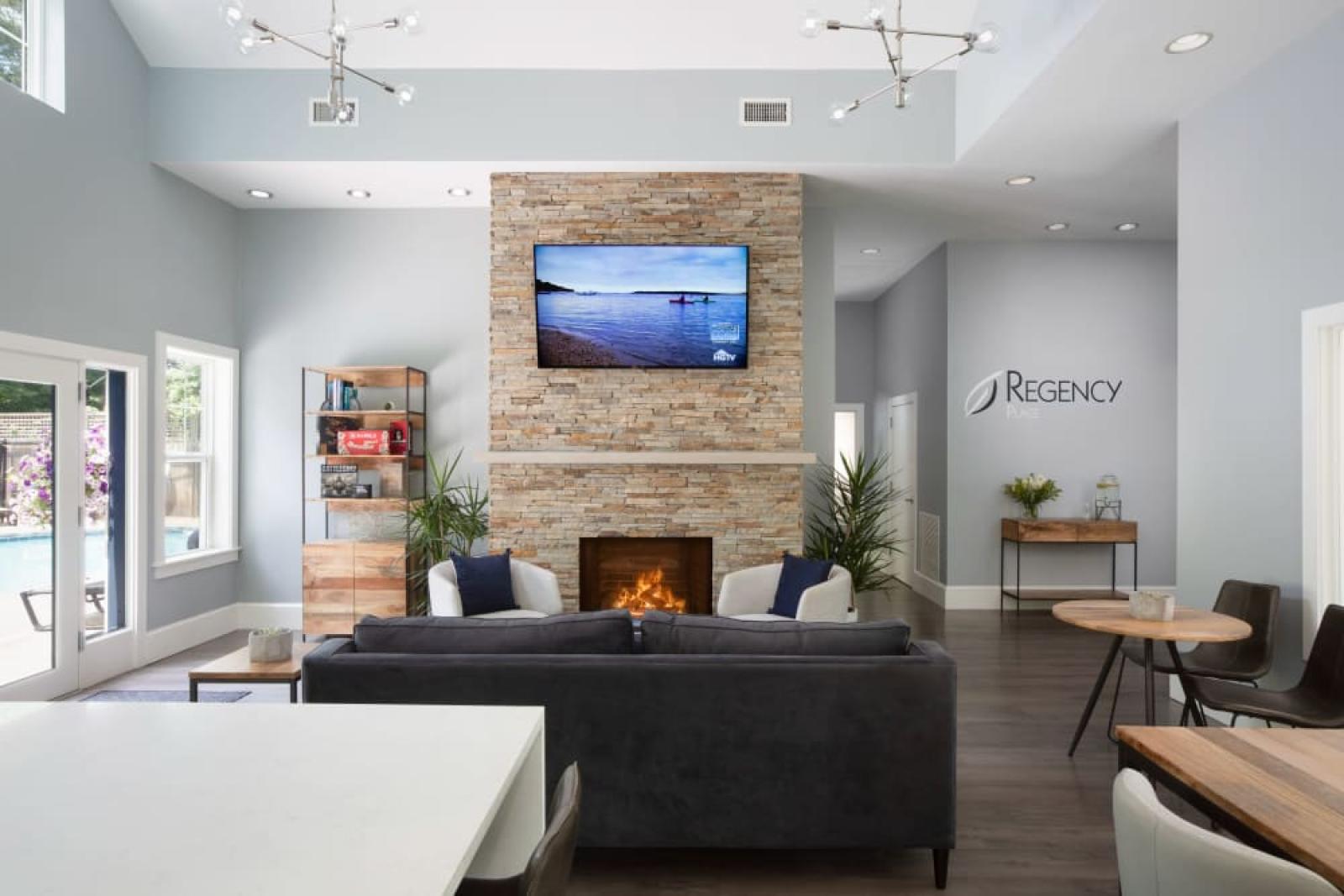 The stylish clubhouse at Oak Enclave Luxury Apartments features a contemporary design, a cozy stone fireplace, and elegant seating areas for residents to relax and socialize.