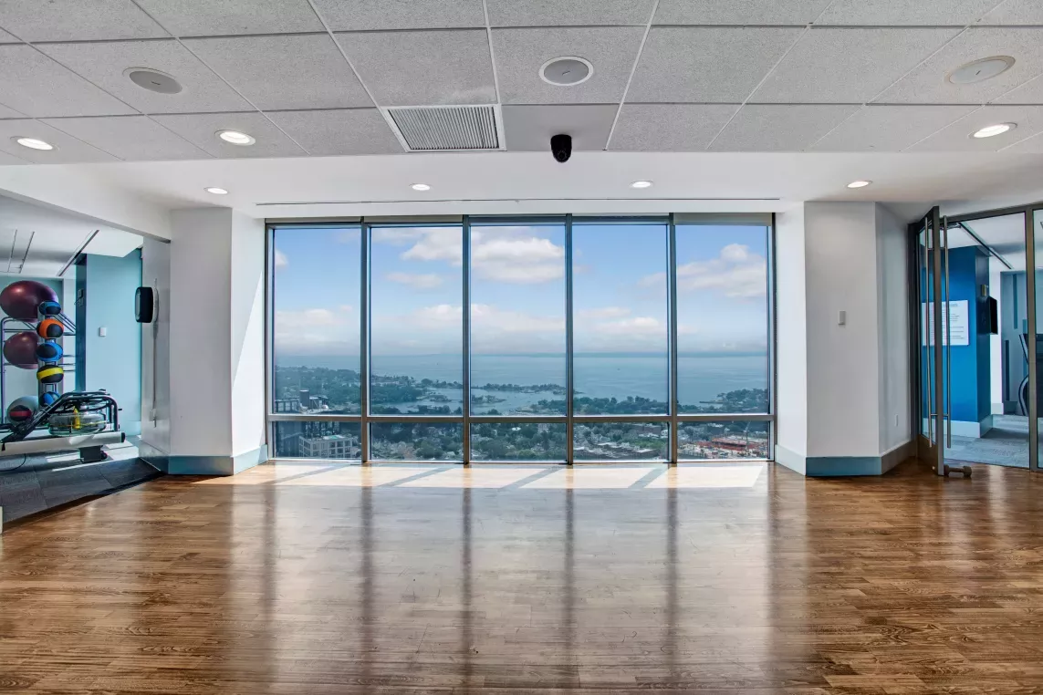 Bright yoga and exercise room with floor-to-ceiling windows showcasing a panoramic cityscape.