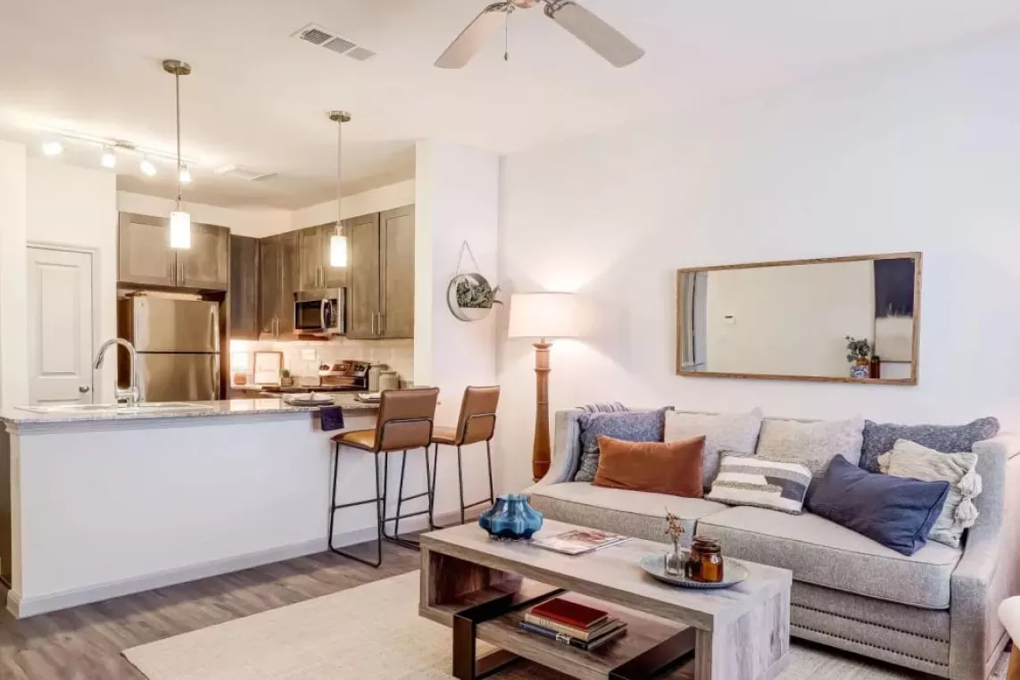 Open-concept living area with a cozy seating arrangement and a view of the contemporary kitchen at The Emerson at Forney.