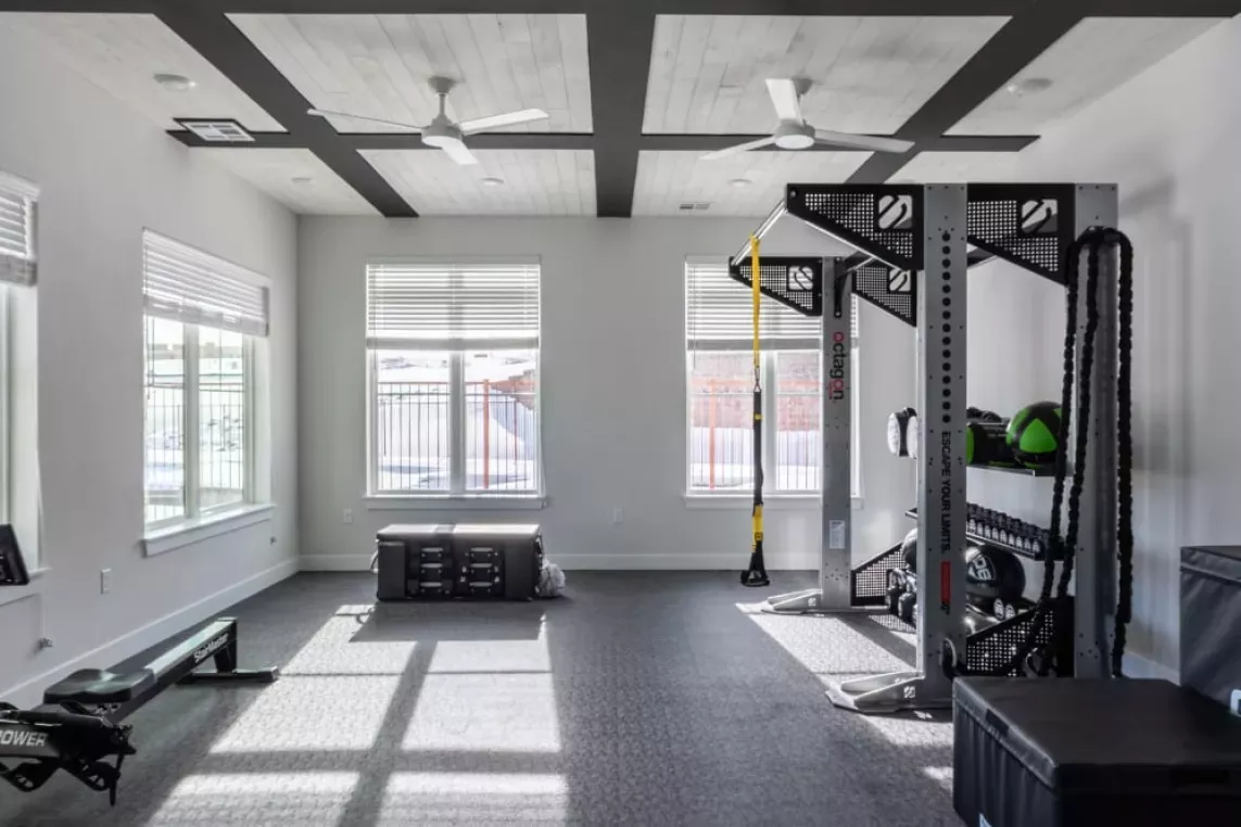 Fitness room showcasing a functional training rig, rowing machine, and ample floor space for diverse workout routines.