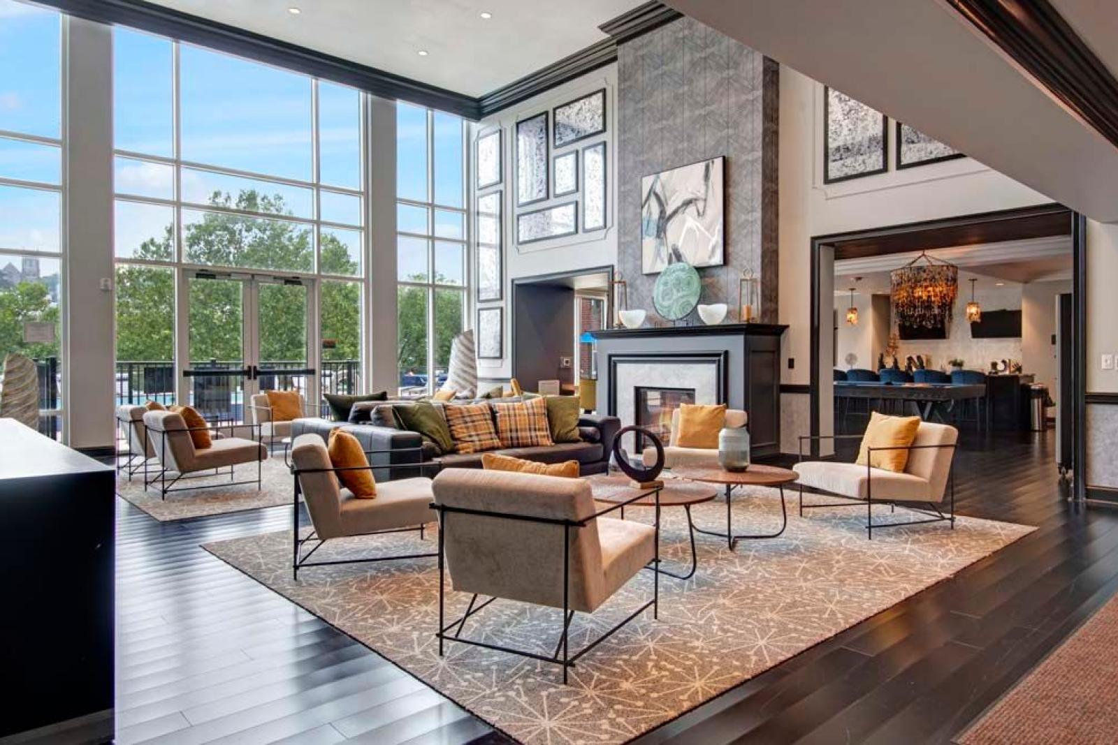 An elegant resident lounge with floor-to-ceiling windows, a cozy seating area, and a modern fireplace.